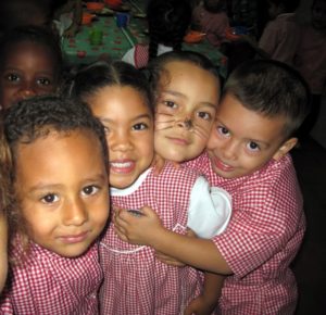 Cuatro niños abrazados mirando la cámara sonrientes