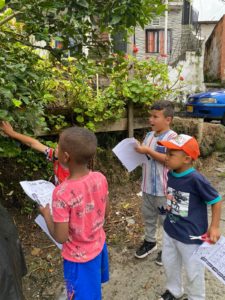 Tres niños investigando y tomando apuntes sobre plantas.