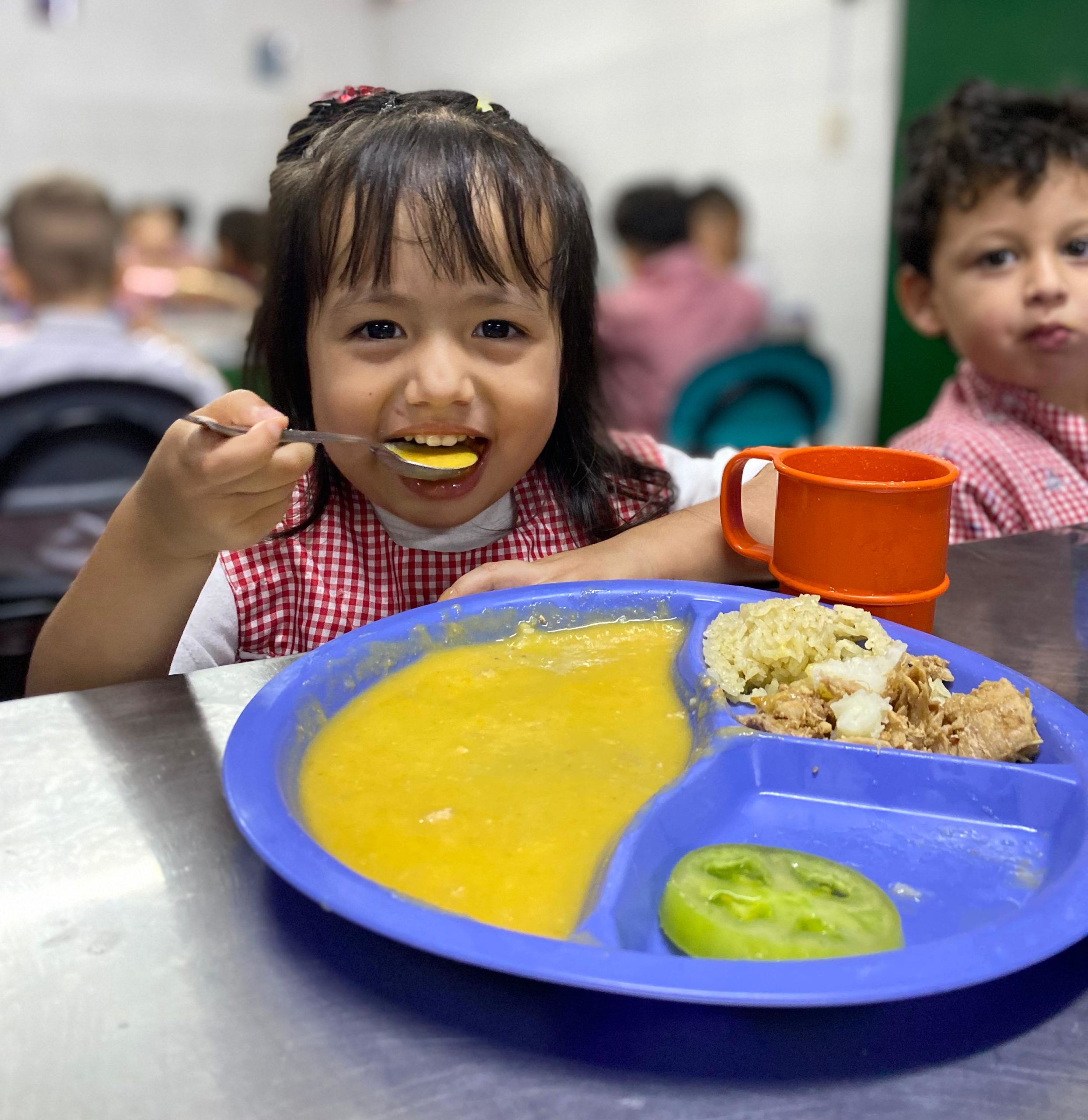 Niña sonriente mientras prueba un poco de su almuerzo.