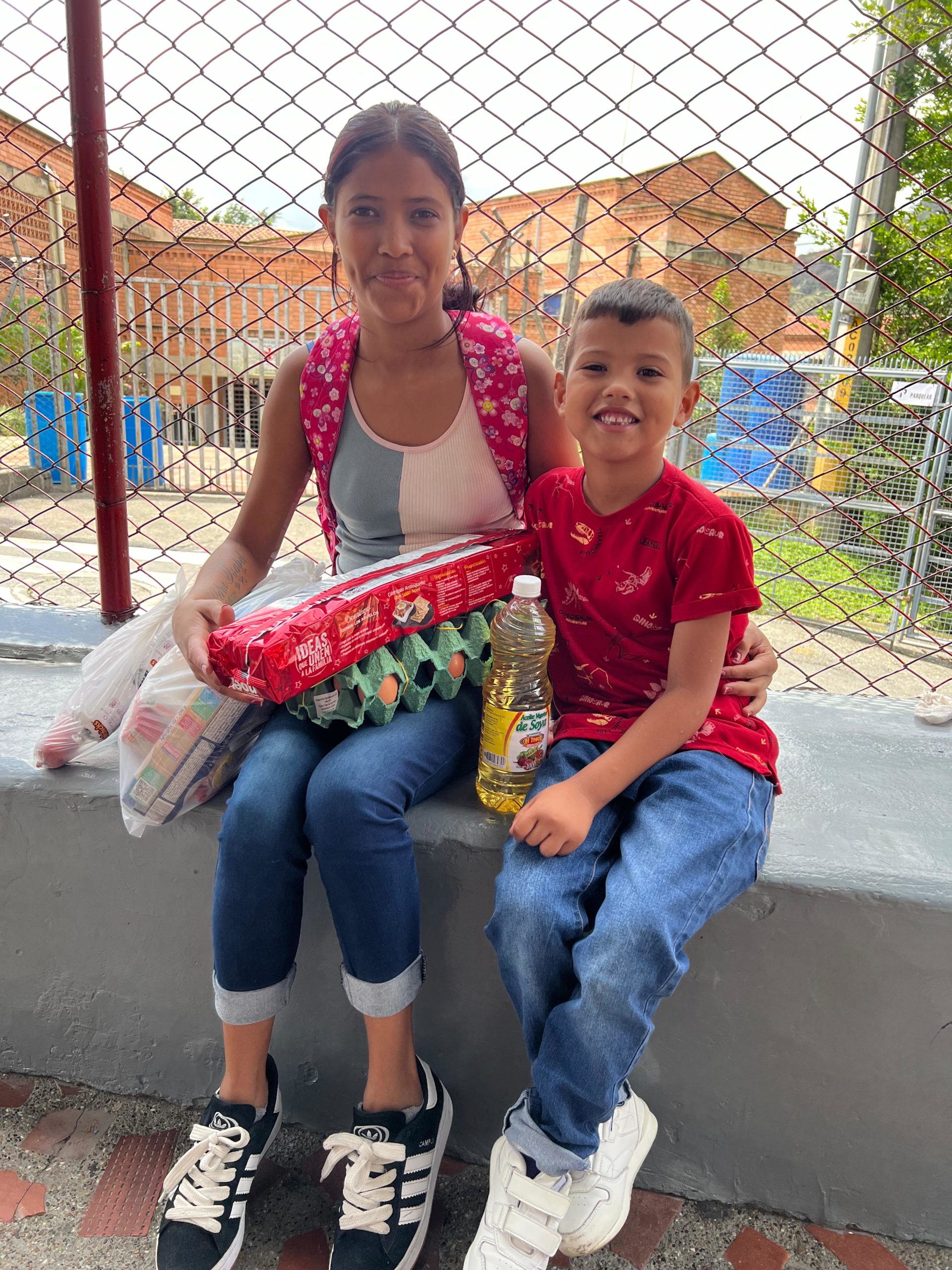 Un niño y una niña sonrientes sosteniendo donaciones realizadas.